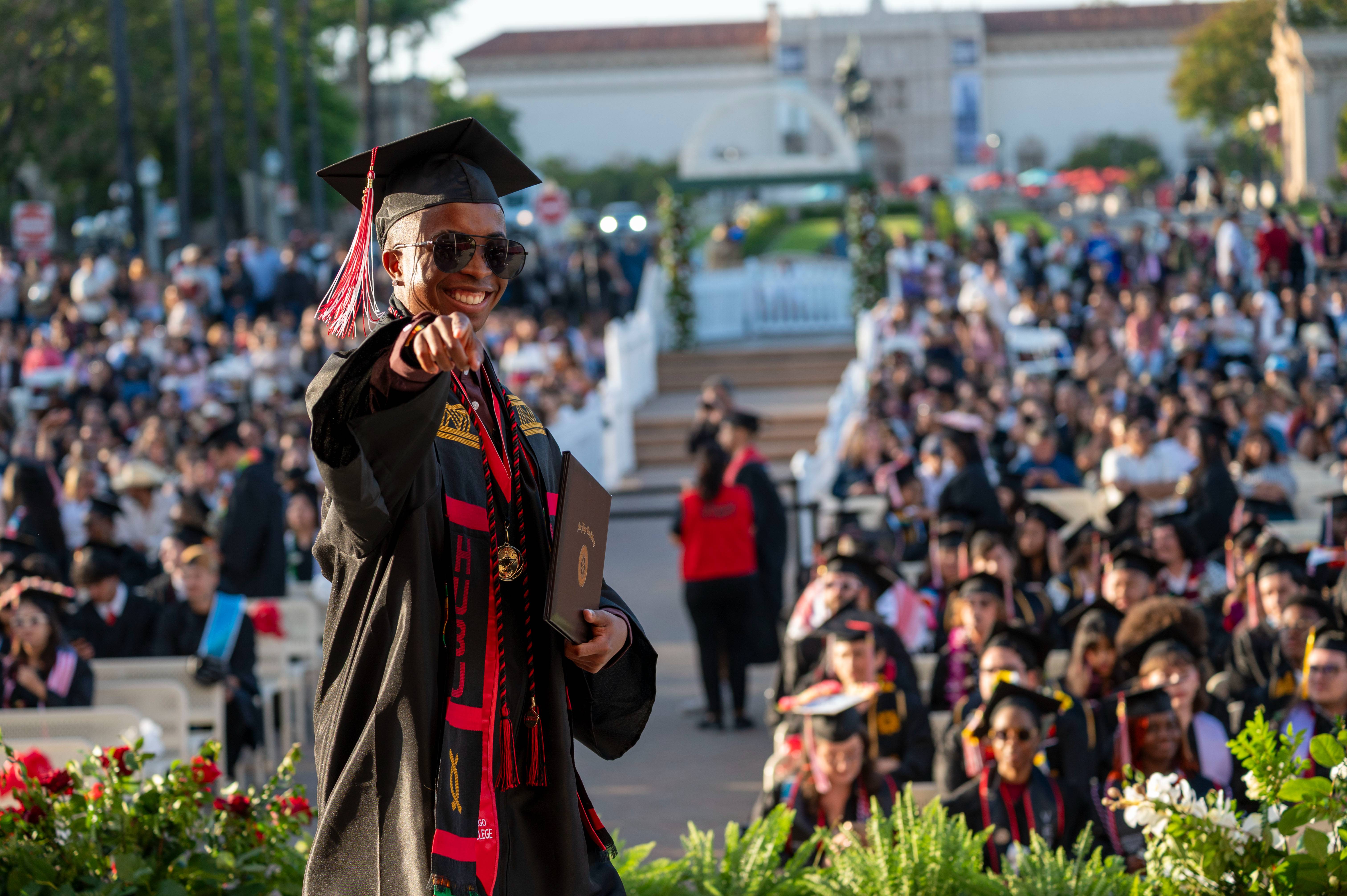 Student smiling and pointing to the camera on graduation day