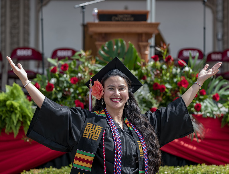 Woman smiling with hands raised at commencement