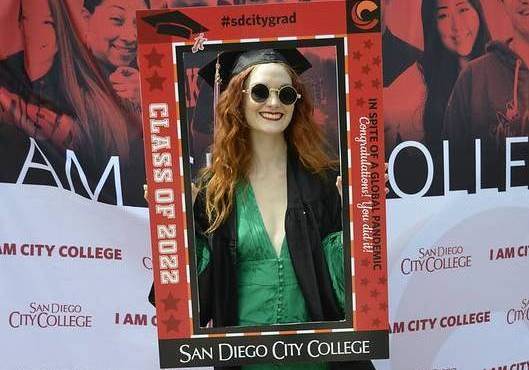 Woman graduate in green dress holding wide picture frame