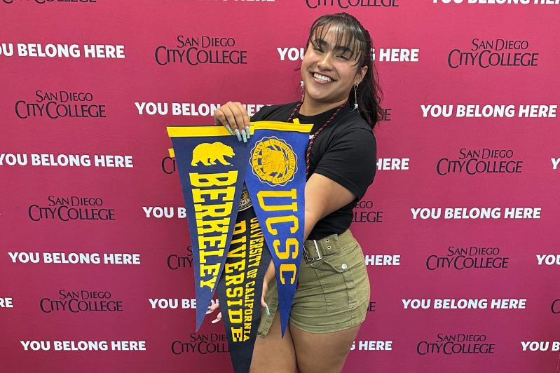 Student holding multiple pennants for universities admitted to