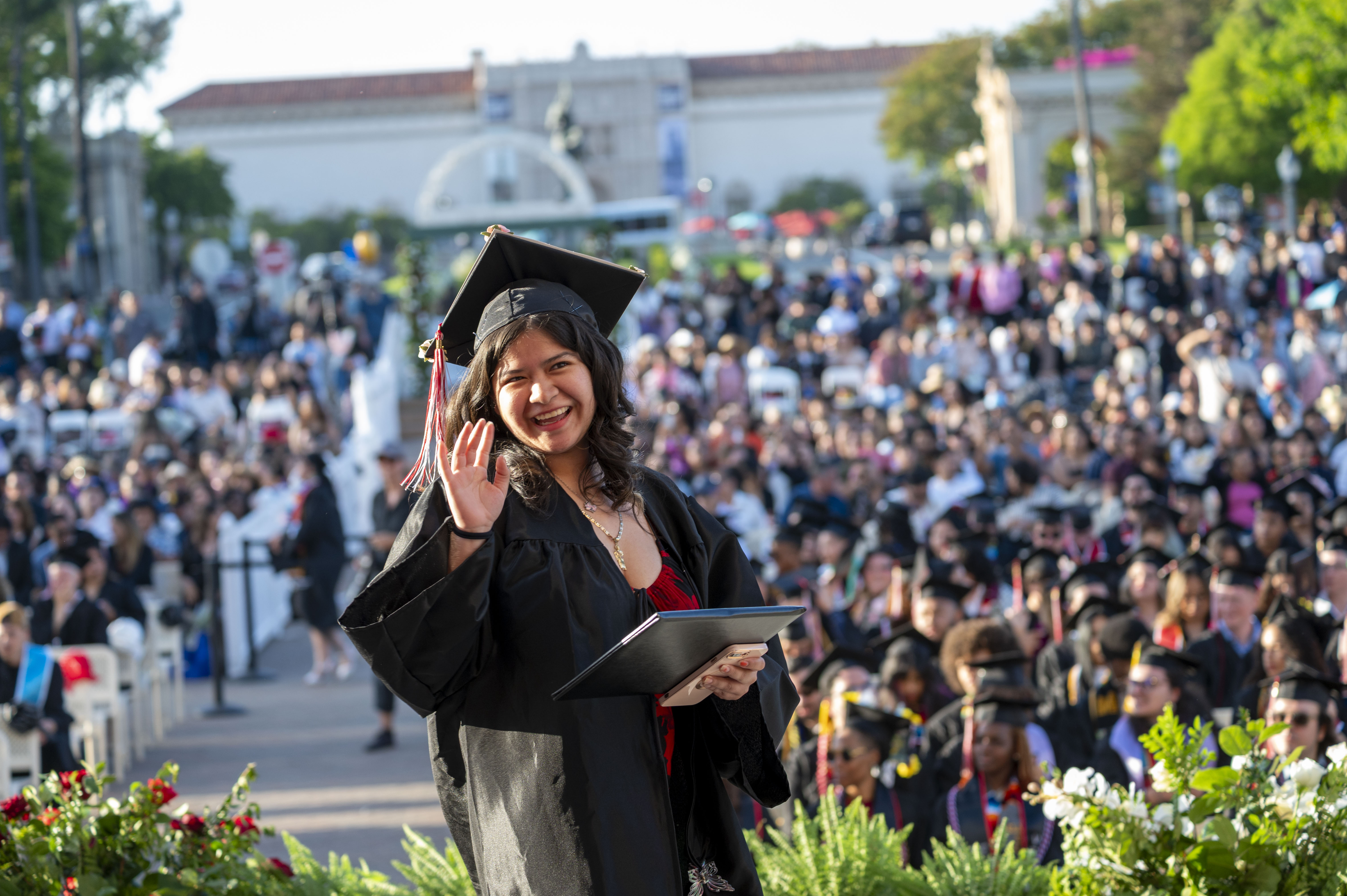Student with diploma waving at graduation