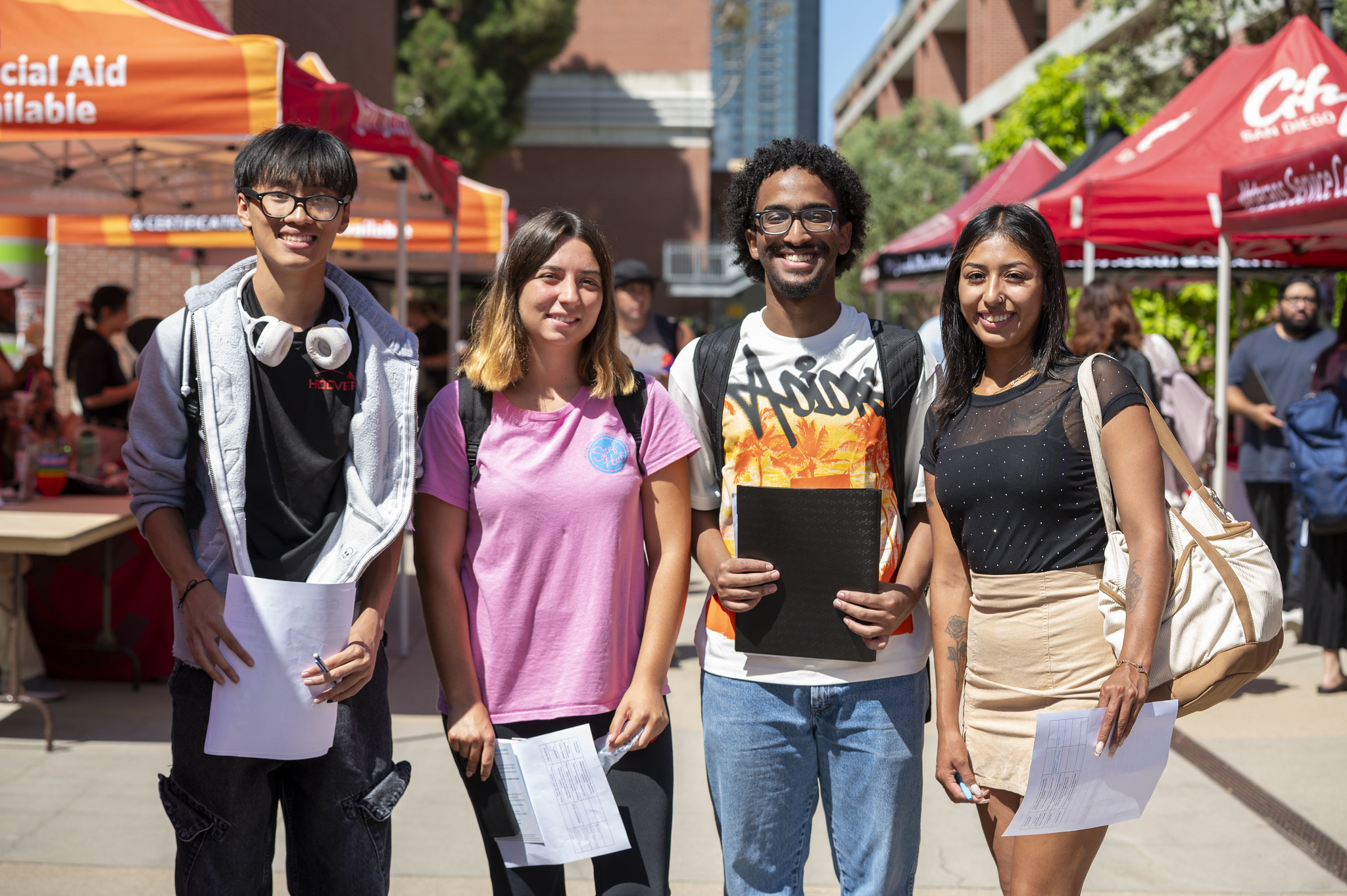 Four students holding materials at a San Diego City College fair.